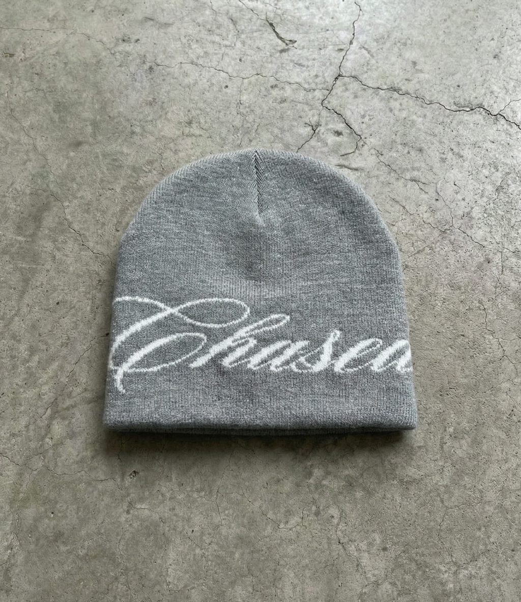 a grey skully beanie with a chasedvision design laying on the floor, perfect for cold weather or to complete an outfit.
