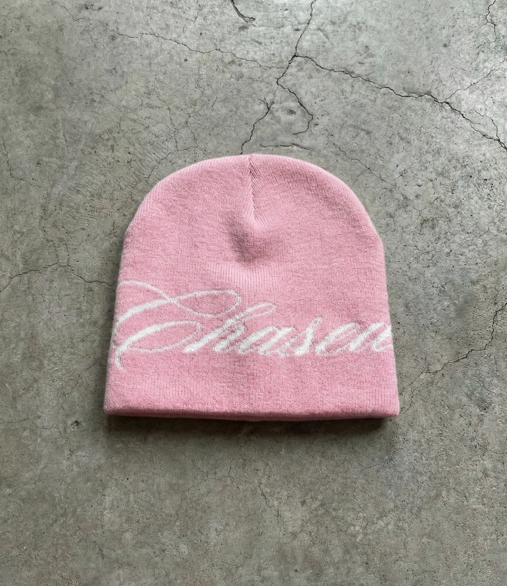 a pink skully beanie with a chasedvision design laying on the floor, perfect for cold weather or to complete an outfit.