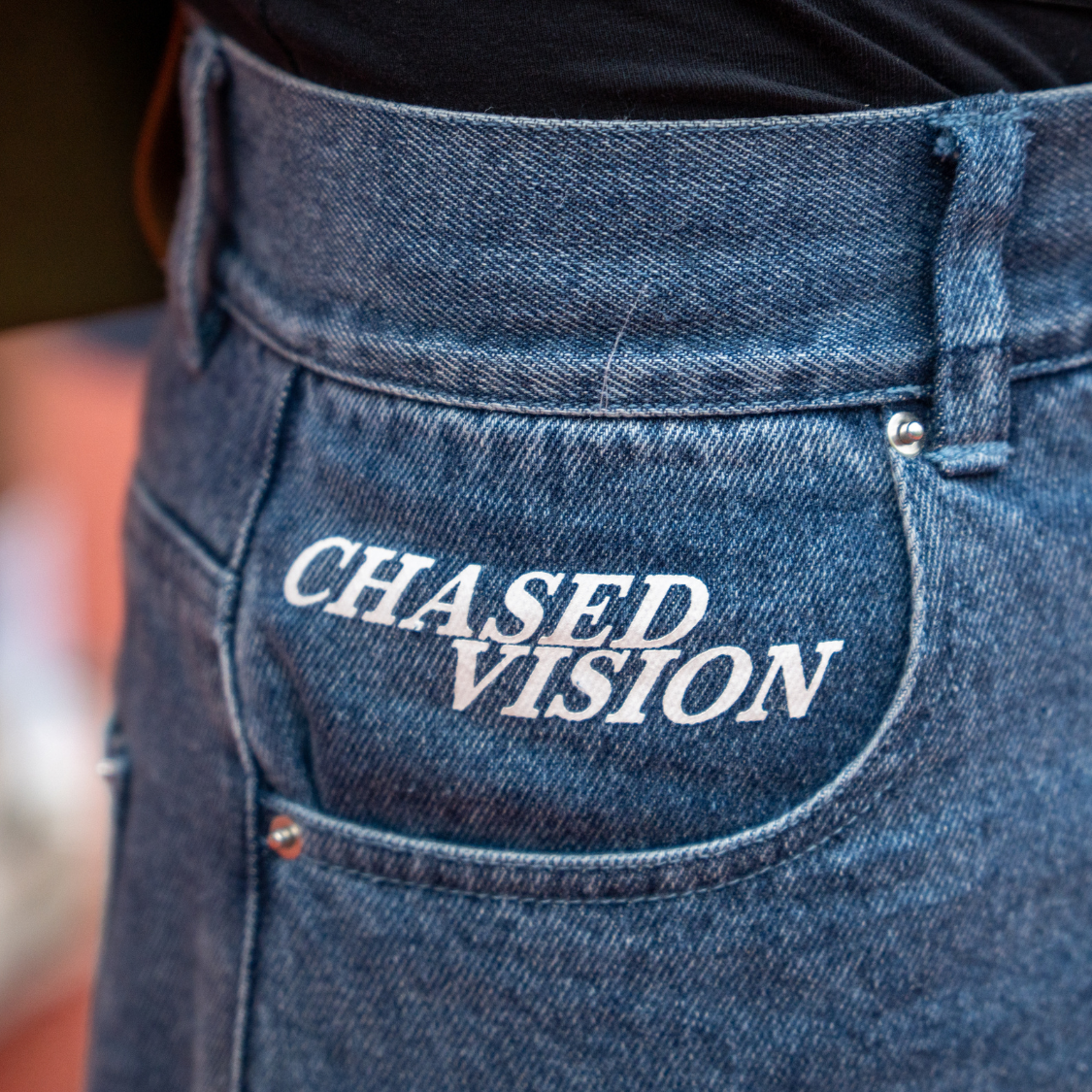 Blue washed jorts with "Chased Vision" branding, featuring high quality fabric, perfect fit, and detailed design with a keychain attached.