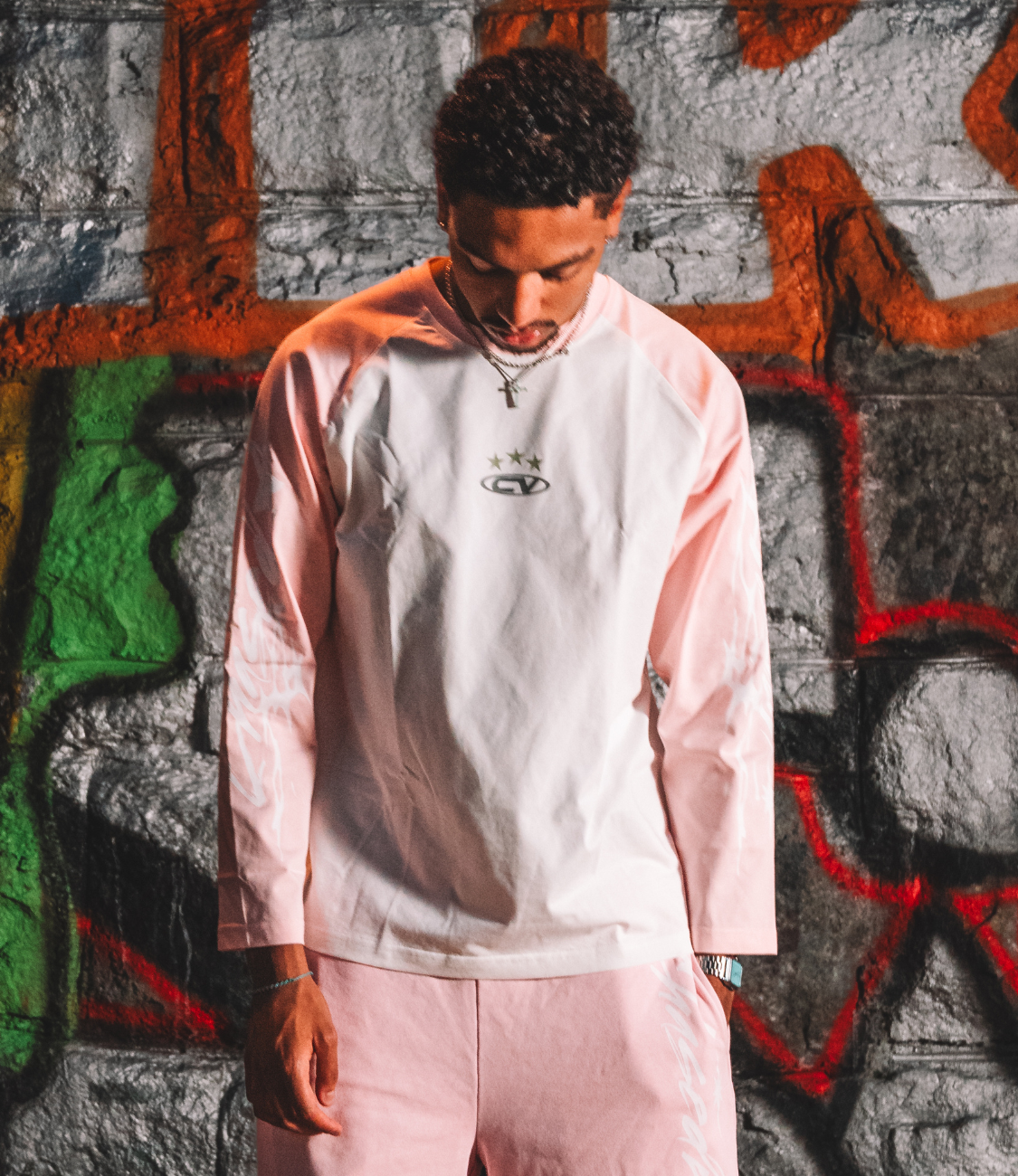 Young man wearing a pink longsleeve shirt with a stylish design, perfect for summer shorts and casual outfits.